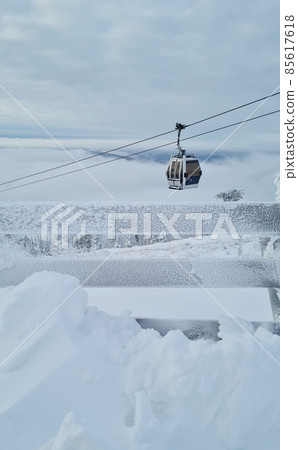 Empty white red closed ski lift cabin no people and white dramatic snowy mountains background. End of season concept. Ski resorts closure Empty white red closed ski lift cabin no people and white dramatic snowy mountains background. End of season concept. Ski resorts closure 85617618