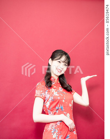 beauty asian woman wear cheongsam and smile in red background. beauty asian woman wear cheongsam and smile in red background. 85619474