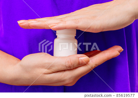 Female hands hold a white plastic bottle with medicine or vitamins Female hands hold a white plastic bottle with medicine or vitamins 85619577