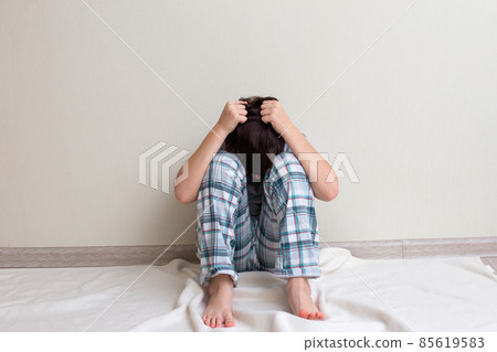 Teen boy in pajamas sitting on the floor Teen boy in pajamas sitting on the floor 85619583