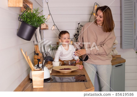 Young woman and little son play in the kitchen with dry red beans, together Young woman and little son play in the kitchen with dry red beans, together 85619586