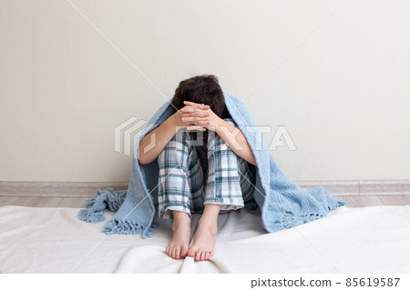 Teen boy sad, sitting in pajamas on the floor Teen boy sad, sitting in pajamas on the floor 85619587