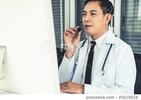 Doctor wearing headset talking actively on video call in a clinic or hospital . Doctor wearing headset talking actively on video call in a clinic or hospital . 85620028