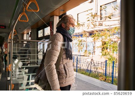 Mature man adjusting face mask while riding train or bus 85620659