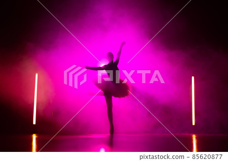 Silhouette of ballerina is practicing elements in studio with neon pink light. Young woman dancing 85620877