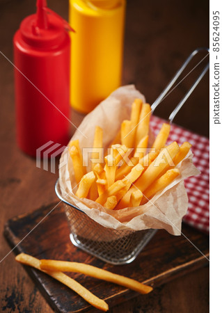 French fries in a metal mesh basket on a wooden board. Fast food concept, american food 85624095
