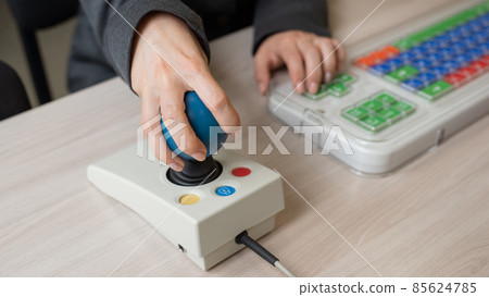 Woman with cerebral palsy works on a specialized computer mouse. Woman with cerebral palsy works on a specialized computer mouse. 85624785