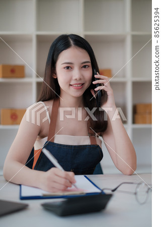 Business owner confirm address to send to customer orders talking by cell phone before pack products. Successful SME entrepreneur concept. 85625394