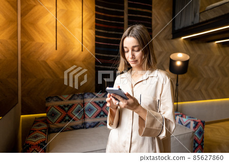 Woman using phone at modern apartment Woman using phone at modern apartment 85627860