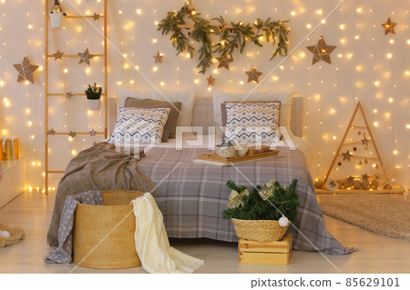 Christmas decorated bedroom with garlands, stars, xmas tree, ladder, presents and bed close up photo Christmas decorated bedroom with garlands, stars, xmas tree, ladder, presents and bed close up photo 85629101