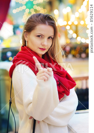 happy blond girl in red scarf show warning sign with point finger happy blond girl in red scarf show warning sign with point finger 85629114