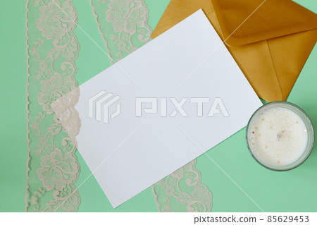 simple invitation mockup with golden envelope, candles and lace on mint green background simple invitation mockup with golden envelope, candles and lace on mint green background 85629453