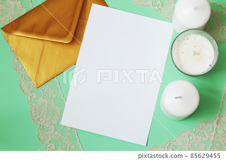 simple invitation mockup with golden envelope, candles and lace on mint green background simple invitation mockup with golden envelope, candles and lace on mint green background 85629455