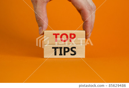 Top tips symbol. Concept words Top tips on wooden blocks on a beautiful orange background. Businessman hand. Business and Top tips concept, copy space. 85629486