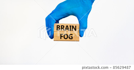 Medical and COVID-19 Pandemic brain fog symbol. Doctor hand in blue glove holds wooden blocks with words 'brain fog'. Beautiful white background. Copy space. Medical and covid-19 brain fog concept. 85629487