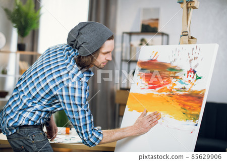 Inspired man drawing colorful pattern with hands on easel Inspired man drawing colorful pattern with hands on easel 85629906