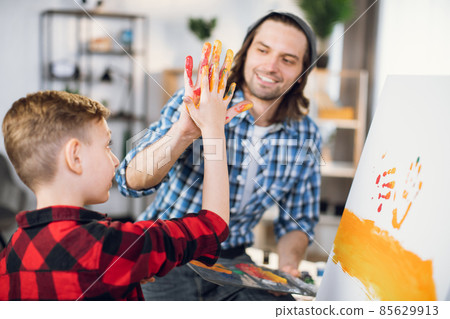 Man giving high five to son while painting on easel Man giving high five to son while painting on easel 85629913