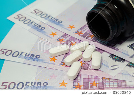 Money pills. Medicine pills on euro bills on a blue background. Covid-19 coronavirus pills are in Money pills. Medicine pills on euro bills on a blue background. Covid-19 coronavirus pills are in 85630840