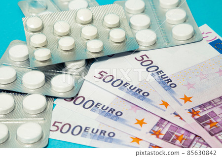 Money pills. Medicine pills on euro bills on a blue background. Covid-19 coronavirus pills are in Money pills. Medicine pills on euro bills on a blue background. Covid-19 coronavirus pills are in 85630842