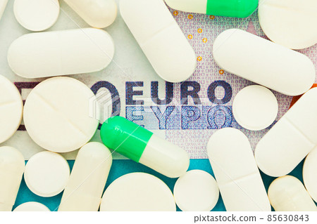 Money pills. Medicine pills on euro bills on a blue background. Covid-19 coronavirus pills are in Money pills. Medicine pills on euro bills on a blue background. Covid-19 coronavirus pills are in 85630843