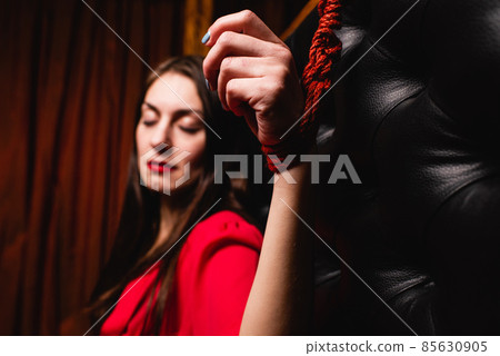 Close-up of a woman's hand tied to the bed. Close-up of a woman's hand tied to the bed. 85630905