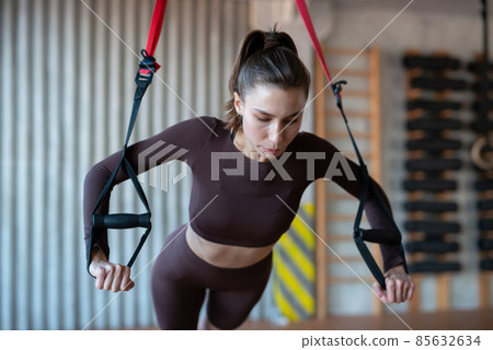 Fit woman doing push-up exercise with trx Fit woman doing push-up exercise with trx 85632634