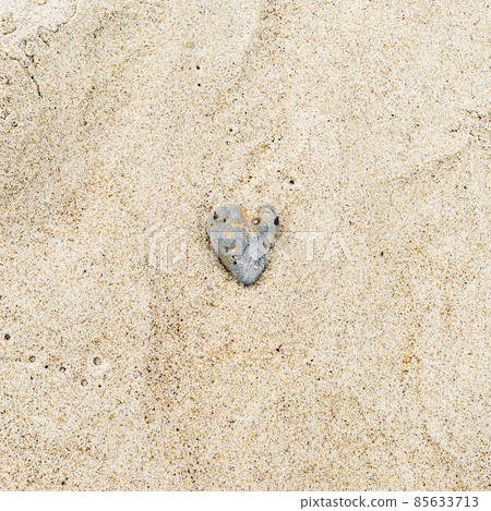 Heart-shaped gray sea rock on sandy beach, square photo 85633713