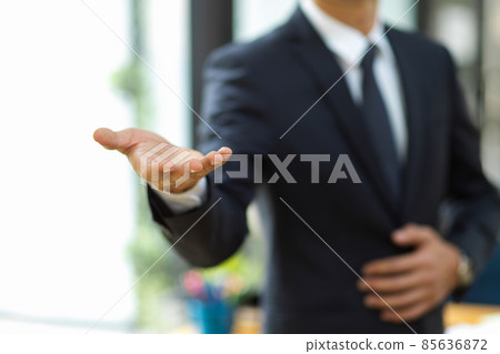 A businessman in formal suit extending hand for handshake at camera. 85636872
