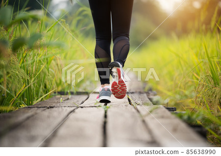 woman feet running on wooden path in field 85638990