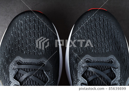 Black running shoes with mesh and black laces close-up on a dark background Black running shoes with mesh and black laces close-up on a dark background 85639899