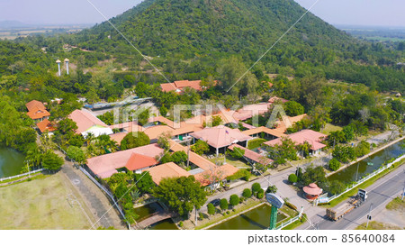 Aerial view of Thai village, hotel resort on green mountain hills with forest trees, Ratchaburi, Thailand. Nature landscape in travel trip and vacation. Aerial view of Thai village, hotel resort on green mountain hills with forest trees, Ratchaburi, Thailand. Nature landscape in travel trip and vacation. 85640084