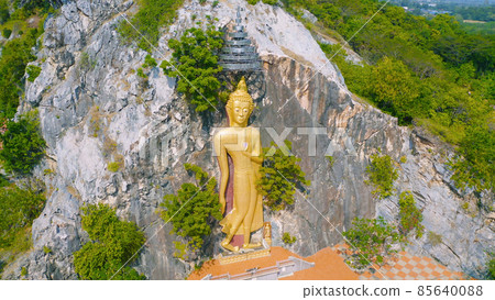 Aerial view of Phra Putthachai Tham Rusi Khao Ngu, golden buddha pagoda stupa, Ratchaburi, Thailand with green mountain hills and forest trees. Thai buddhist temple architecture. Tourist attraction. Aerial view of Phra Putthachai Tham Rusi Khao Ngu, golden buddha pagoda stupa, Ratchaburi, Thailand with green mountain hills and forest trees. Thai buddhist temple architecture. Tourist attraction. 85640088