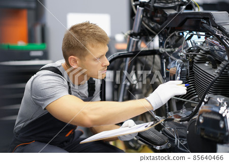 A man in the garage is checking a motorcycle A man in the garage is checking a motorcycle 85640466