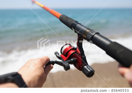Hands hold a fishing rod against the background of sea coast 85640553
