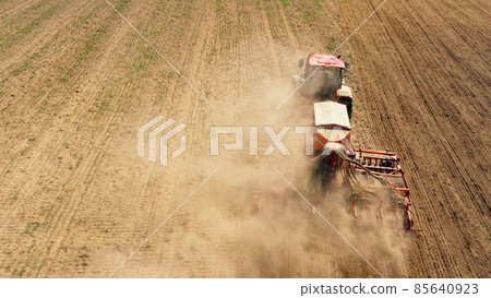 4K Elevated View Tractor With Seed Drill Machine Sowing The Seeds For Crops In Spring Season. Beginning Of Agricultural Spring Season. Countryside Rural Field Landscape 85640923
