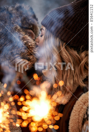 Couple Love Story in Snow Forest Kissing and Holding Sparklers. Couple in Winter Nature. Couple Celebrating. Valentine's day date. Couple Love Story in Snow Forest Kissing and Holding Sparklers. Couple in Winter Nature. Couple Celebrating. Valentine's day date. 85641152