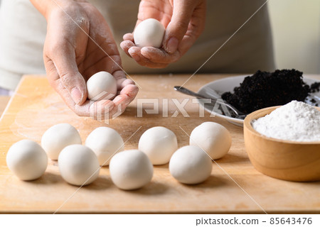 Hand making Tangyuan, Chinese dessert made of ball glutinous rice flour and filled with black sesame 85643476