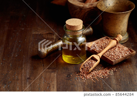 Flaxseeds and linseed oil on an old wooden table. 85644284