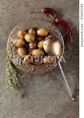 Spicy green olives in olive oil on a old stone table. Spicy green olives in olive oil on a old stone table. 85644298