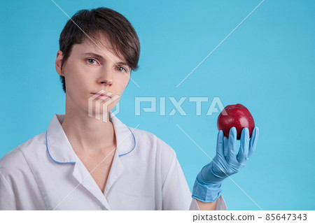 doctor in blue gloves holds a red Apple in hand as an example of healthy eating doctor in blue gloves holds a red Apple in hand as an example of healthy eating 85647343