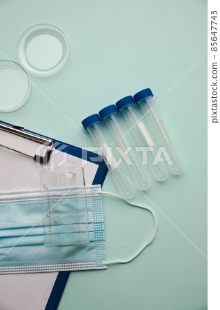 Top view of a watch glass, test tubes and clipboard with mask 85647743