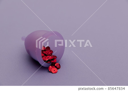 Hygienic menstrual cup with red shining sequins close-up 85647834