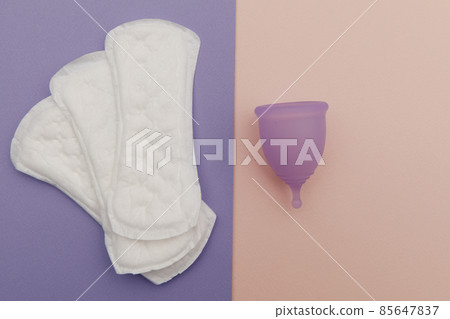 Menstrual cup and sanitary pads on a colorful background. Top view. Concept of women's hygiene and health care Menstrual cup and sanitary pads on a colorful background. Top view. Concept of women's hygiene and health care 85647837