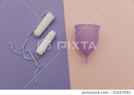 Menstrual cup and tampons on a colorful background. Concept of women's hygiene and health care Menstrual cup and tampons on a colorful background. Concept of women's hygiene and health care 85647845