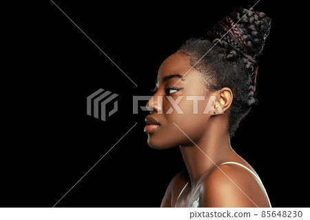 Adorable young african woman with well-kept skin isolated over dark studio background. Natural beauty concept. Side view Adorable young african woman with well-kept skin isolated over dark studio background. Natural beauty concept. Side view 85648230
