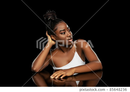 Portrait of young beautiful dark skinned woman without makeup isolated over dark studio background. Natural beauty concept. Portrait of young beautiful dark skinned woman without makeup isolated over dark studio background. Natural beauty concept. 85648236