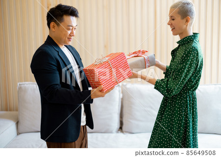 Asian man and young woman giving gifts each other Asian man and young woman giving gifts each other 85649508