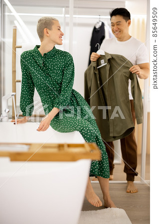 Asian man showing blazer to his caucasian wife Asian man showing blazer to his caucasian wife 85649509