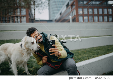 Happy young man taking selfie with his dog outdoors in town. 85649790