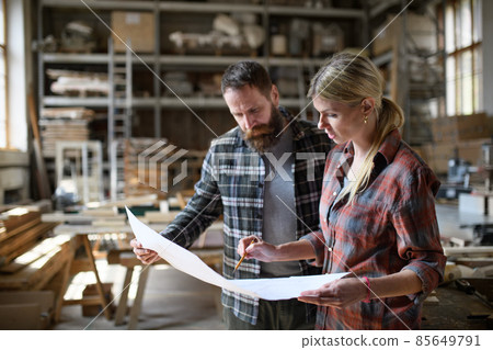 Two carpenters man and woman talking about design of products. Small business concept. Two carpenters man and woman talking about design of products. Small business concept. 85649791